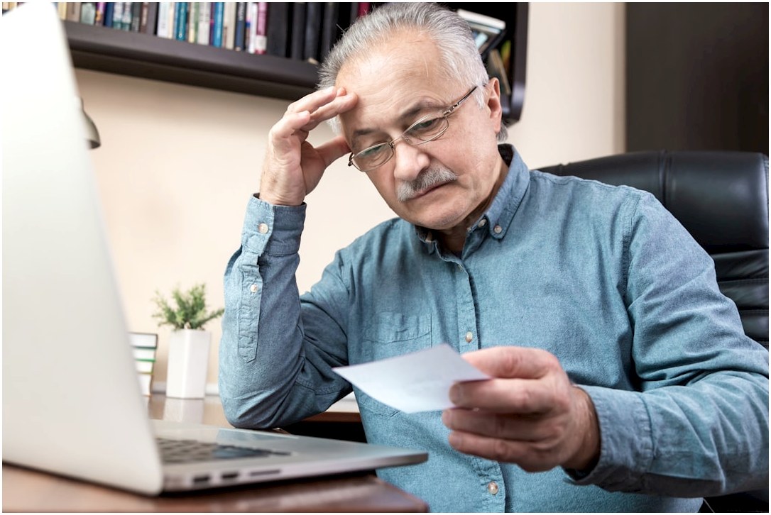 a man holding a pen and looking at a laptop