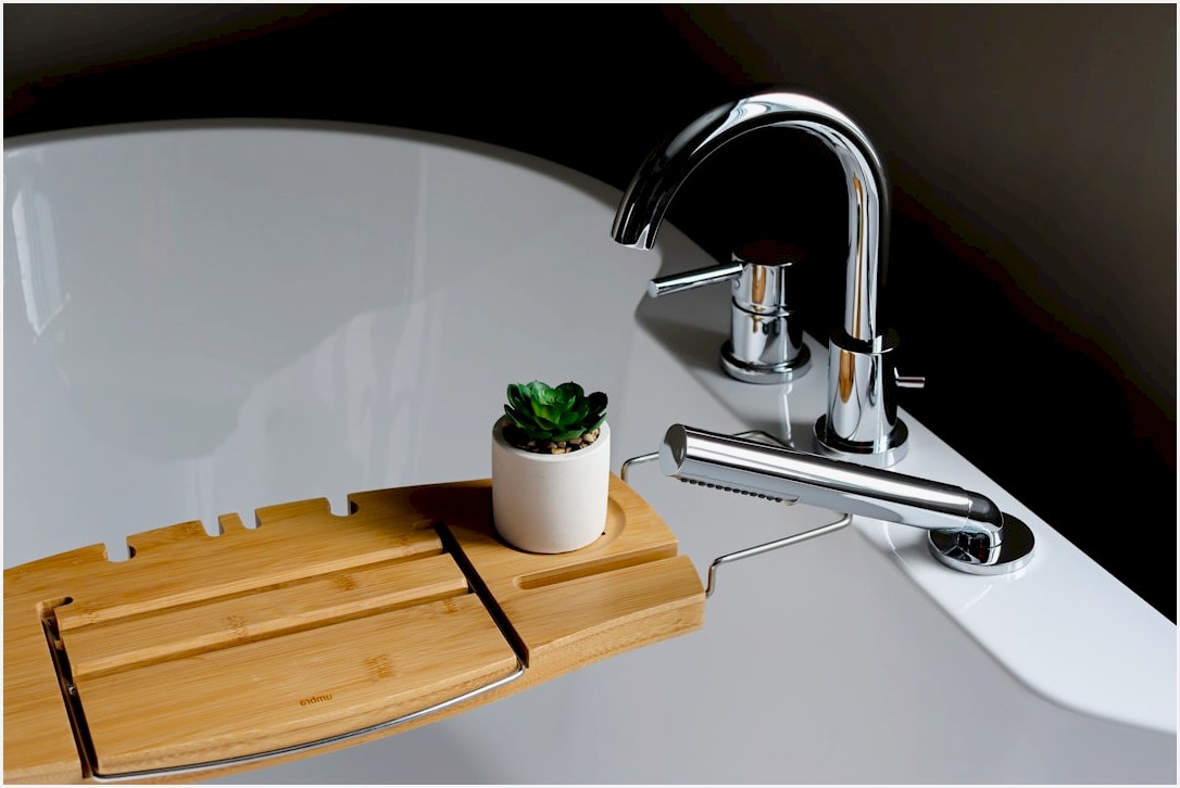 a bathroom sink with a wooden tray holding a succulent