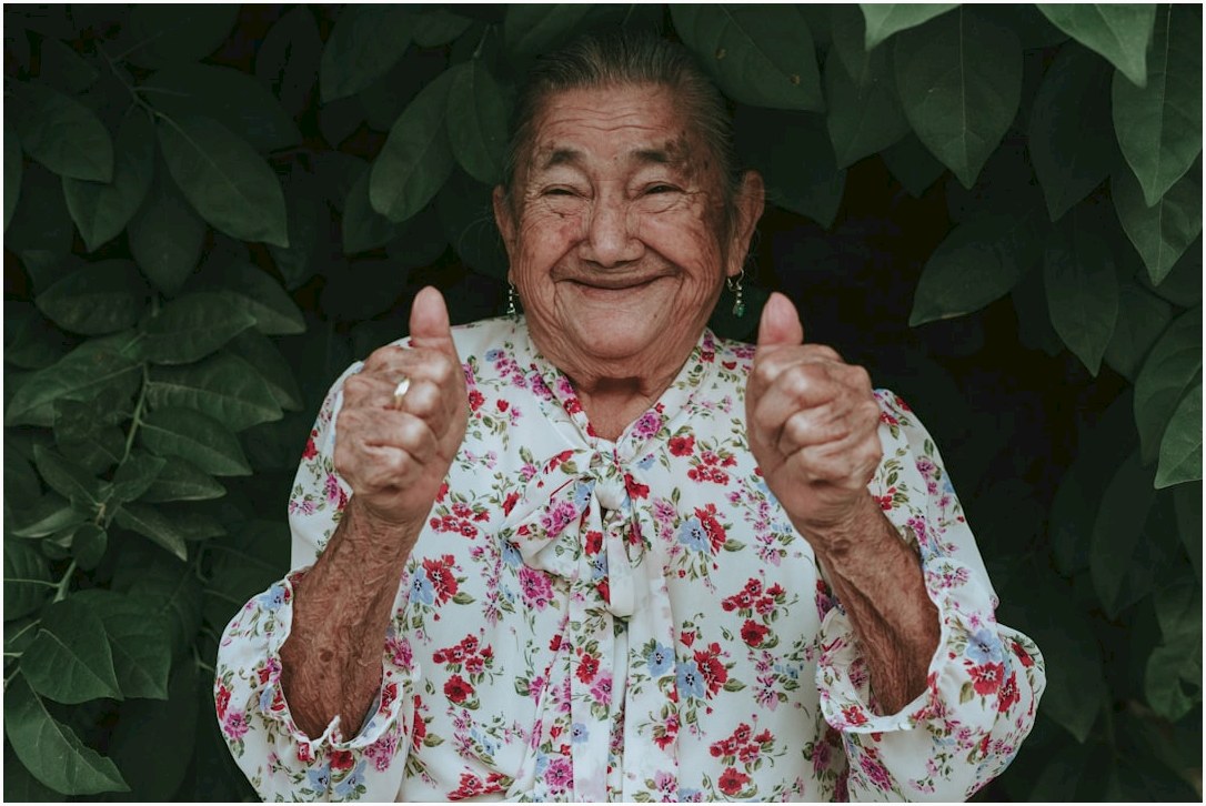 an old woman giving a thumbs up sign