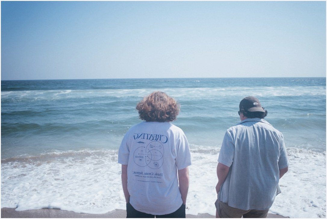 a couple of men standing on top of a sandy beach
