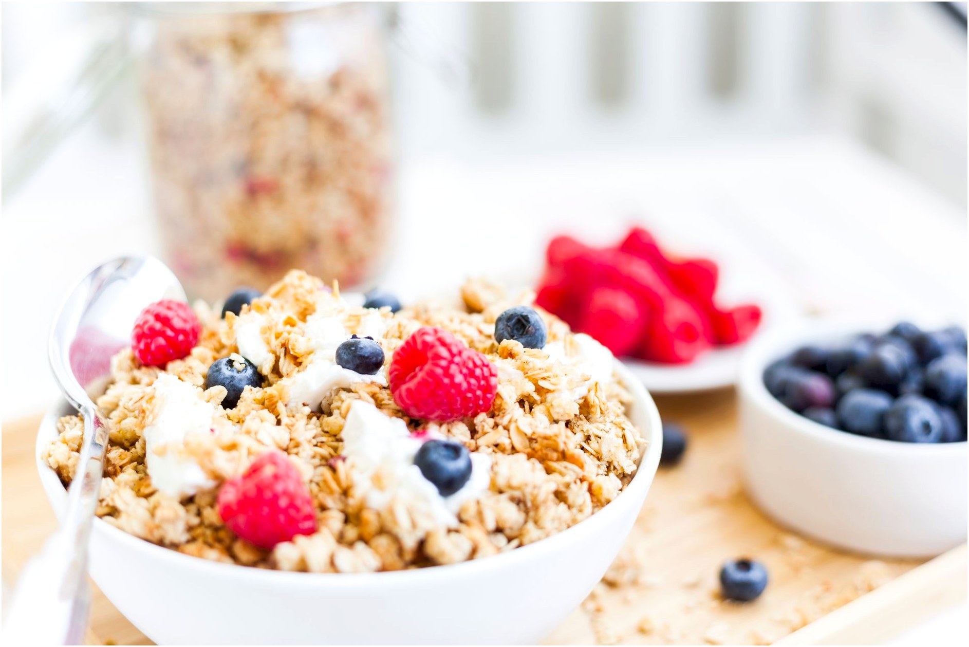 Healthy granola breakfast bowl topped with fresh raspberries and blueberries.