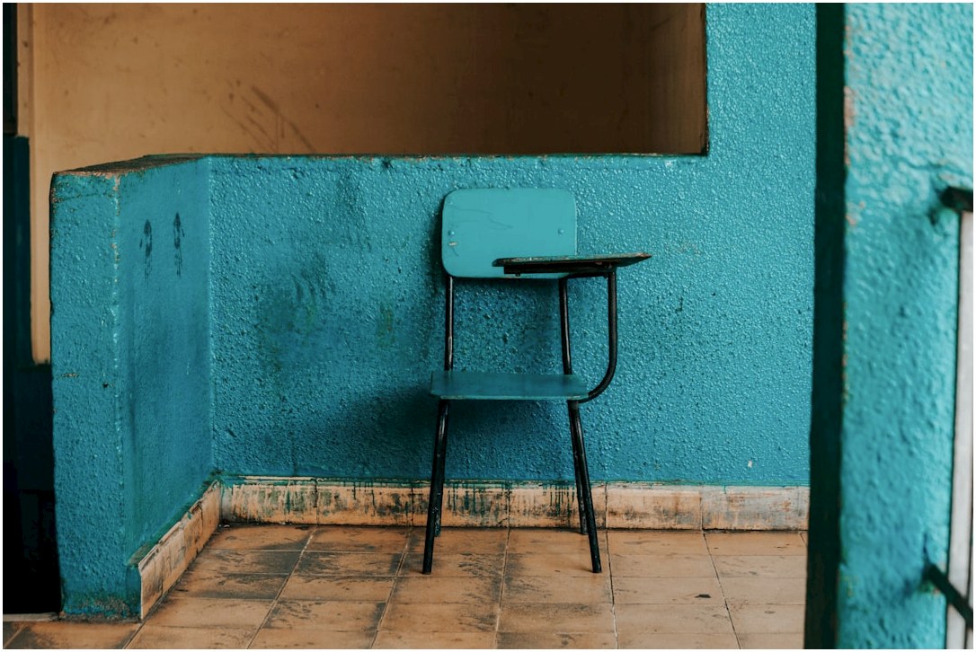blue and black writing chair beside wall