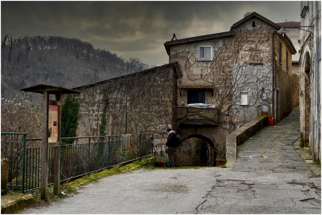 a person standing in a stone alleyway between stone buildings