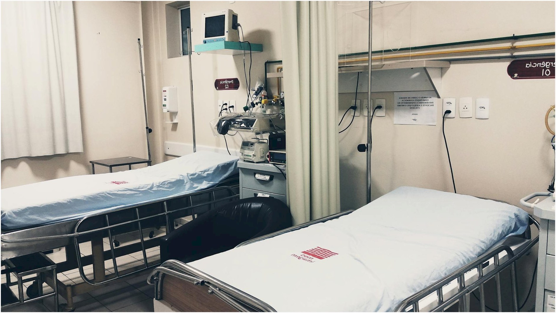 An empty hospital room equipped with two beds, monitoring equipment, and ambient lighting.