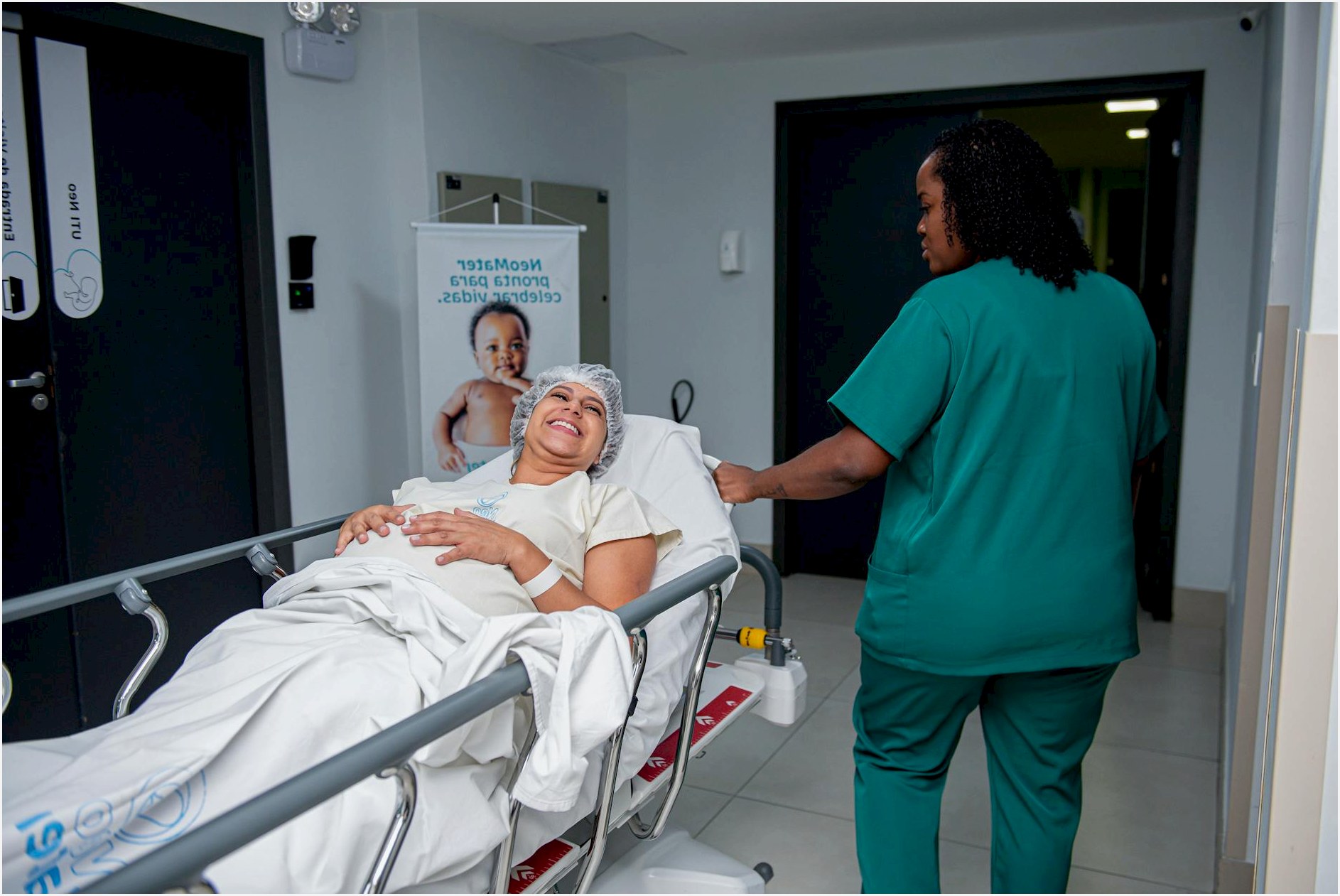 A caring nurse assists a patient in a hospital corridor with a joyful demeanor.