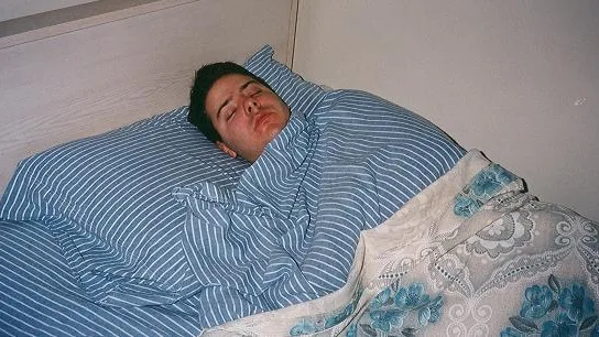 Pessoa dormindo na cama, imagem ilustrativa sobre dor de cabeça ao acordar
