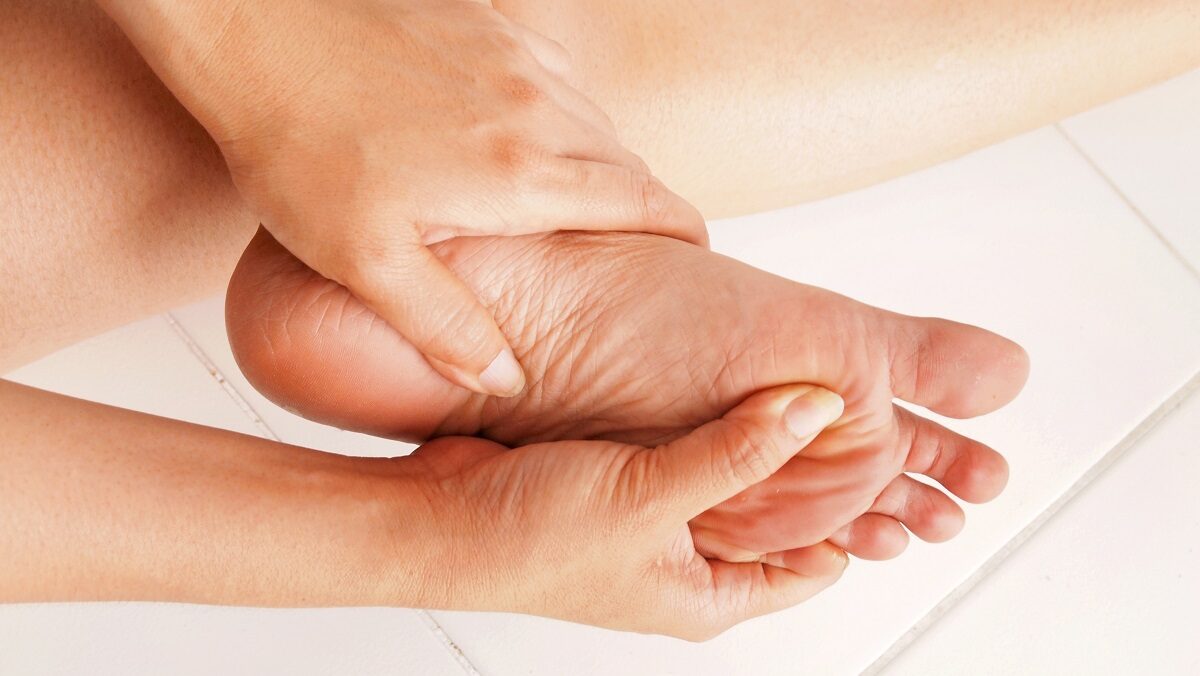Pessoa massageando a região do calcanhar por causa de dor no pé