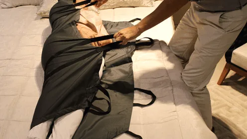 Lençol de transferência com alças sendo usado para reposicionar pessoa acamada na cama