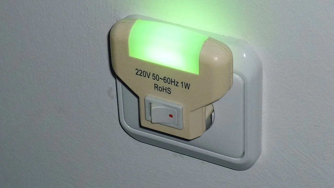 Luz noturna LED instalada em uma tomada, com interruptor manual e iluminação verde