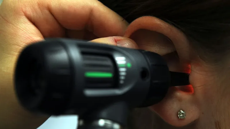 Profissional examina o ouvido com um otoscópio para investigar sensação de ouvido entupido