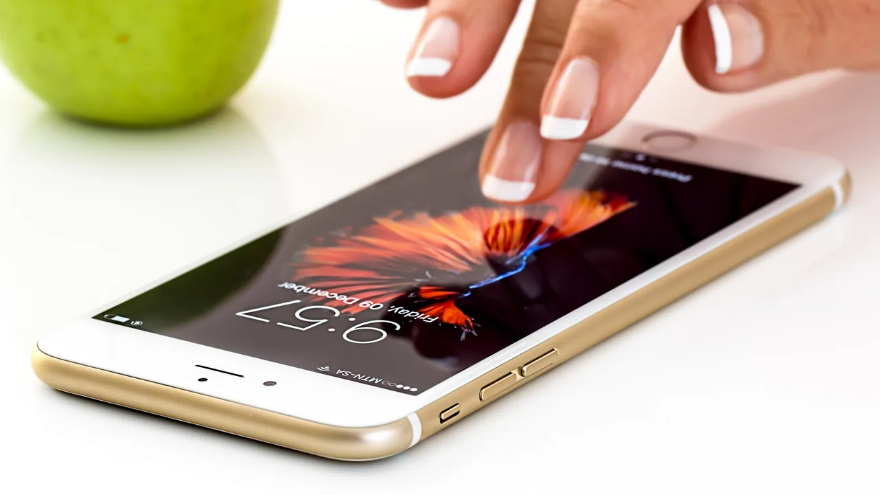Mão tocando a tela de um smartphone sobre uma mesa