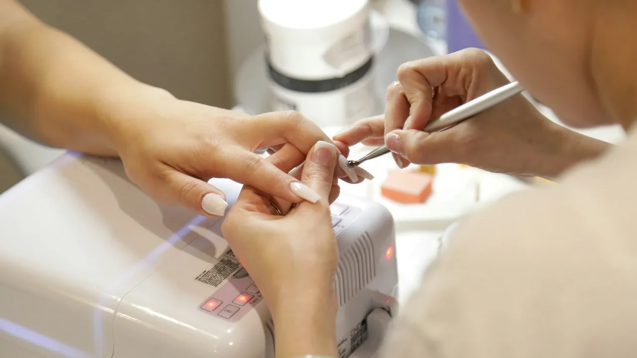 Profissional cuidando das unhas de uma pessoa durante um procedimento de manicure