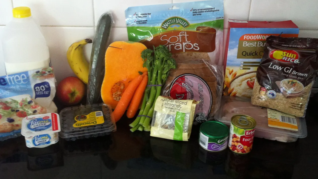 Alimentos variados organizados sobre uma mesa, com frutas, verduras, arroz e laticínios