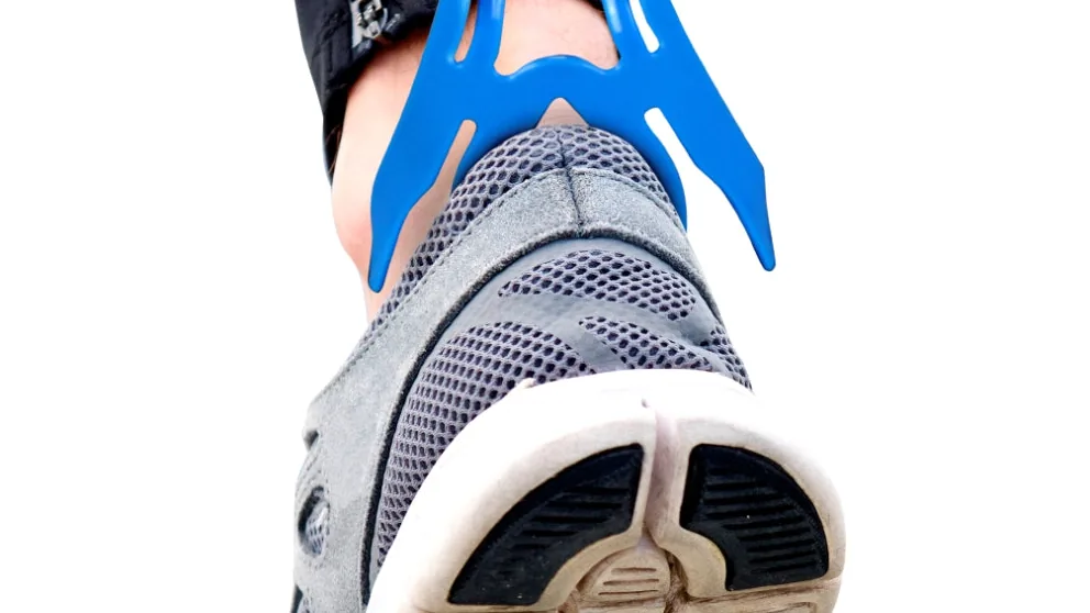 Calçador de meias e sapatos Ortho Pauher sendo usado para retirar um tênis sem precisar se curvar