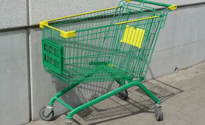 Carrinho de supermercado com rodas, visto de lado, em área externa.