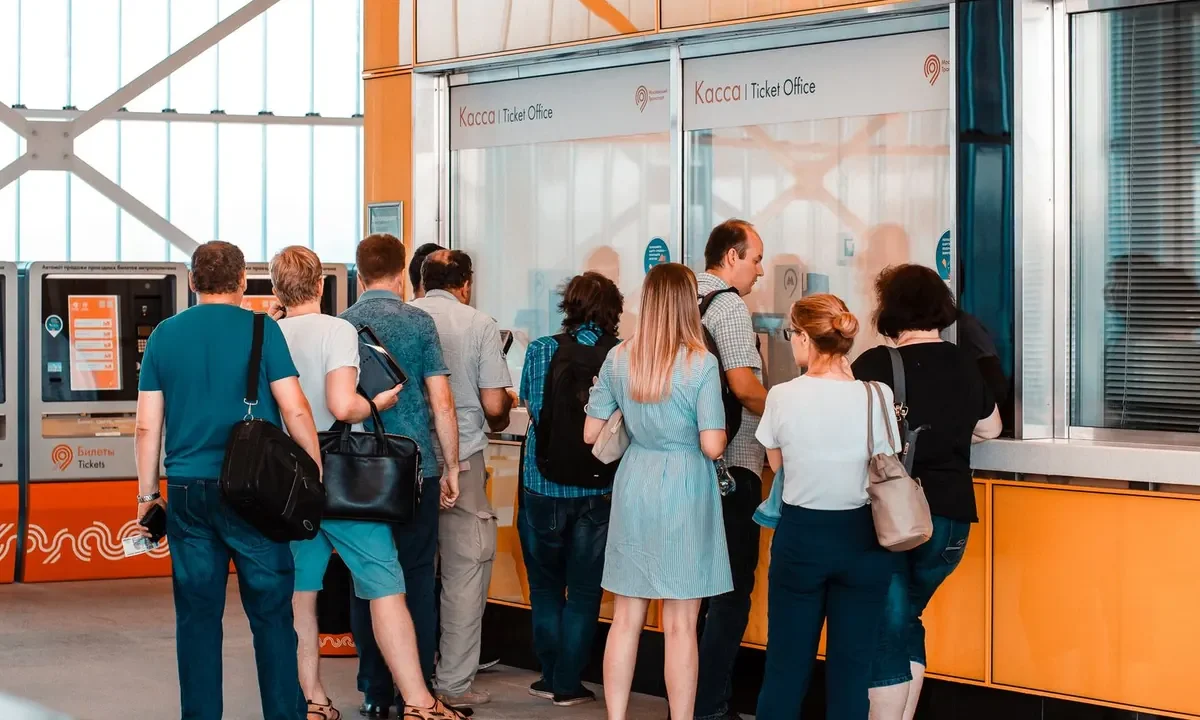 Pessoas aguardam atendimento em uma bilheteria, representando uma fila de serviço ao público.