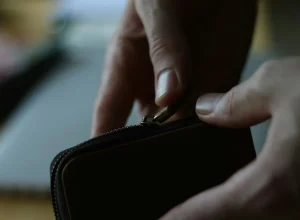 Pessoa abrindo uma carteira com fechamento em zíper