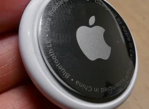 Localizador Apple AirTag branco fotografado de perto, com logotipo da Apple visível.