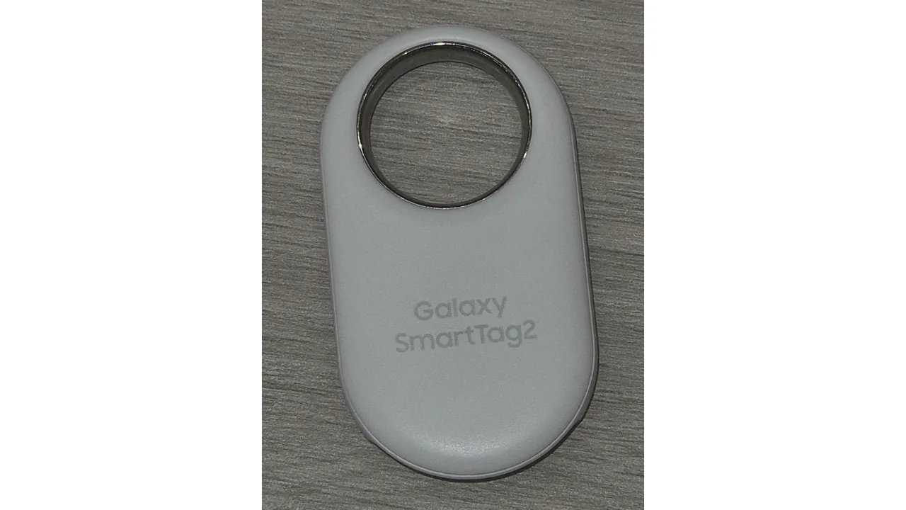 Galaxy SmartTag2 branco sobre uma superfície de madeira, com a inscrição do modelo visível