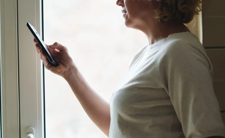 Mulher idosa usando celular para consultar informações digitais