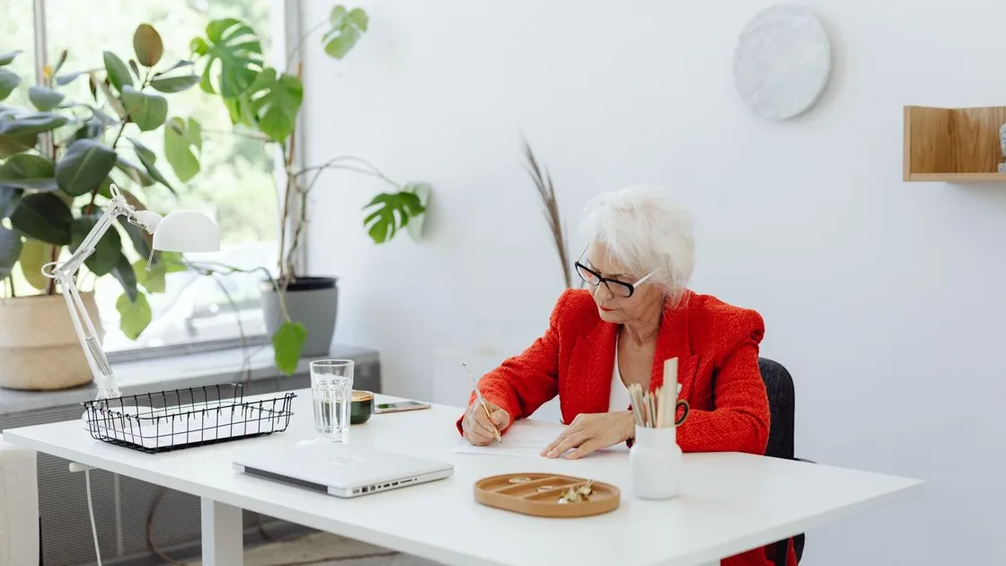 Mulher idosa escrevendo em um documento em casa