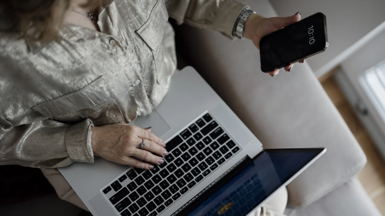 Pessoa usa laptop e smartphone para acessar um serviço digital