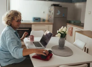 Mulher idosa usa um laptop em casa para acessar um serviço digital