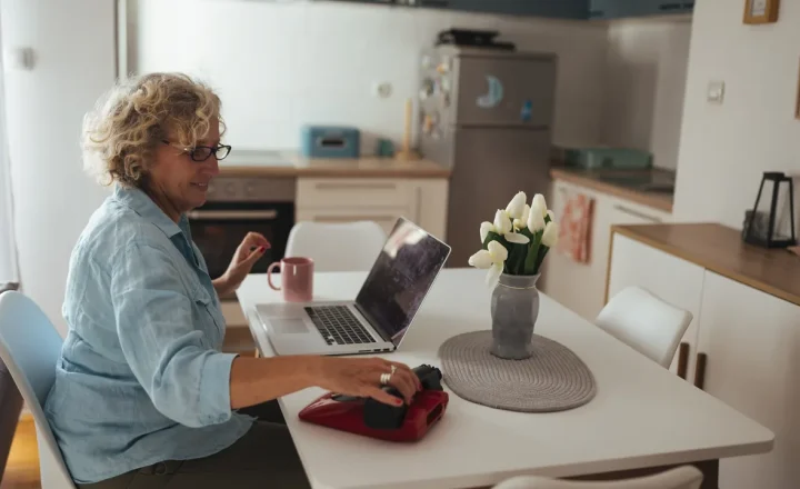 Mulher idosa usa um laptop em casa para acessar um serviço digital