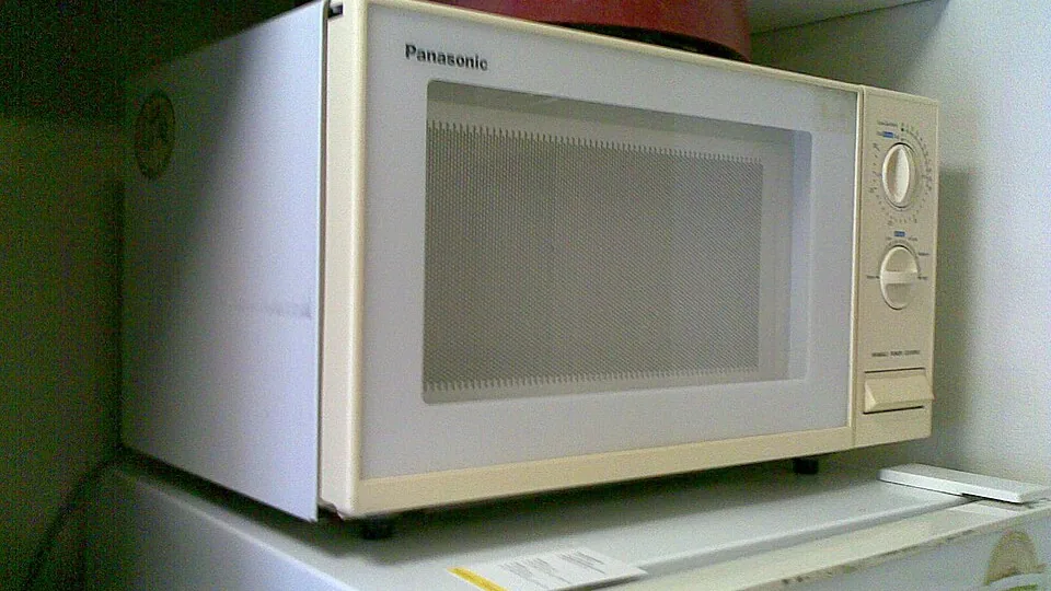 Micro-ondas branco com dois botões giratórios na parte direita do painel