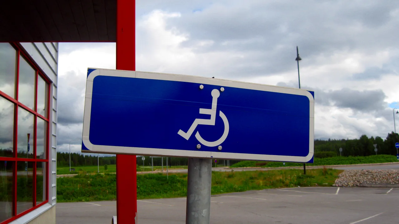 Placa azul com o Símbolo Internacional de Acesso em área de estacionamento