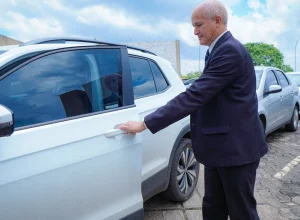 Pessoa abrindo a porta de um carro em área de estacionamento