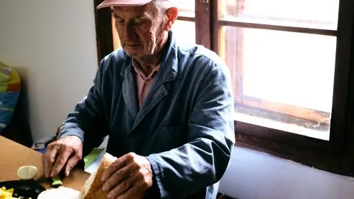 Pessoa idosa preparando uma refeição em casa, imagem relacionada à alimentação e digestão