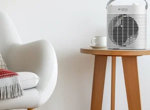 Aquecedor elétrico Cadence MiniConfort branco em uma mesa ao lado de uma poltrona
