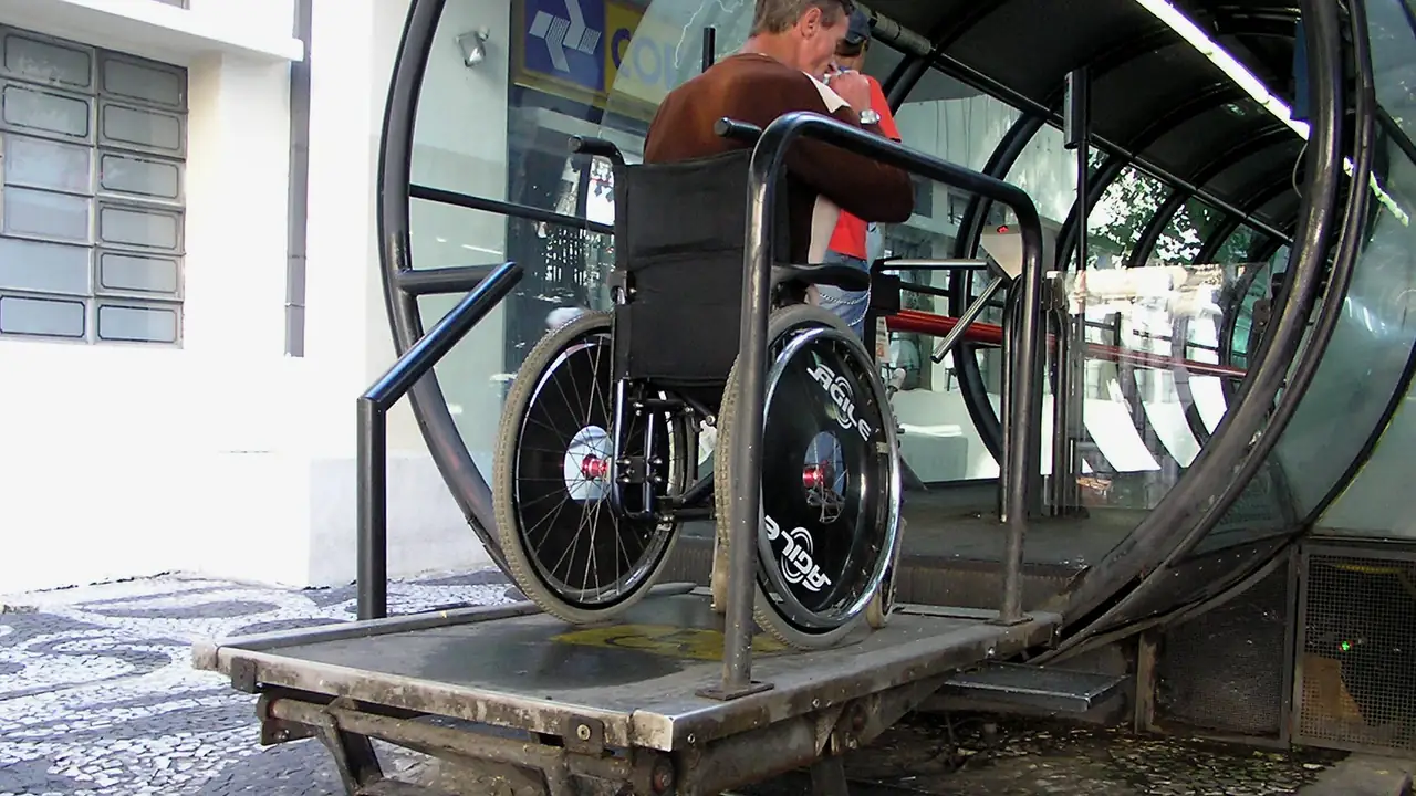 Elevador de ônibus sendo usado para embarcar uma pessoa em cadeira de rodas